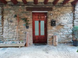 ein Steinhaus mit einer roten Tür davor in der Unterkunft Cal Jardiner in Rialp