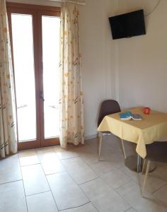 una camera con tavolo, televisore e finestra di Epi Apartments a Lourdata