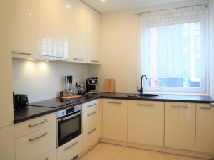 kuchnia z białymi szafkami, zlewem i oknem w obiekcie Apartament 3 pokoje, parking, balkon - Gdańsk Centrum w Gdańsku