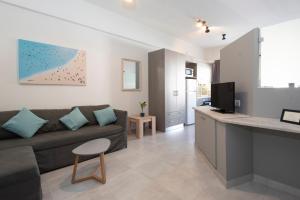 a living room with a couch and a tv and a kitchen at D. Apartments in Kalamata