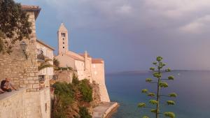 拉布Apartment Lavanda garden的坐在教堂旁墙上的女人,水