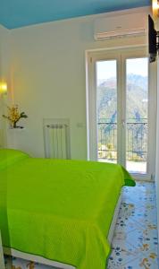 a bedroom with a green bed and a window at Palazzo Mansi in Ravello