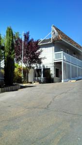 un edificio blanco con un estacionamiento delante de él en Mother Lode Lodge, en Mariposa