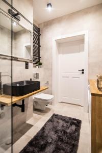 a bathroom with a black tub and a toilet and a sink at Apartament MALTA COMFORT Wes Quality Suite in Poznań +37 photos