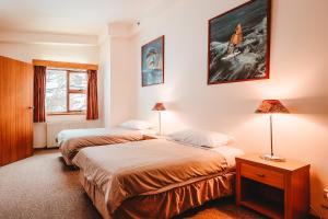 two beds in a room with two lamps and a window at Boonoona Ski Lodge in Perisher Valley