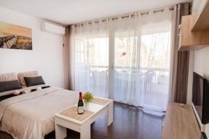 Un dormitorio con una cama y una mesa con una botella de vino en Anne, en Salou