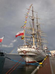 un grand navire amarré dans l'eau avec un arc-en-ciel en arrière-plan dans l'établissement Mirella Centrum Gdyni, à Gdynia