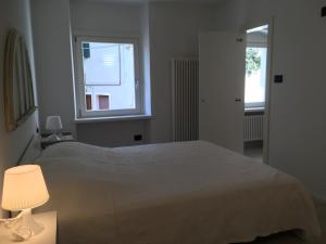 a bedroom with a bed with a lamp and a window at Appartamenti Ora del Garda in Nago-Torbole