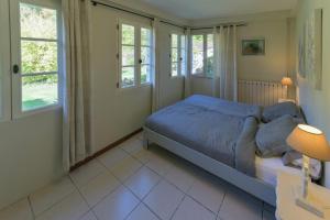 a bedroom with a bed and two windows at Le Prieuré L´Atelier in Lanzac