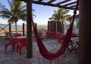 eine Terrasse mit roten Hängematten, Tischen und Strand in der Unterkunft Marina Clube in São Pedro da Aldeia