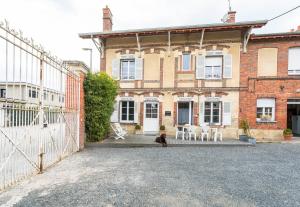 un chat assis devant un bâtiment en briques dans l'établissement Le Gîte De Romane Domaine du vendangeoir, à Vinay