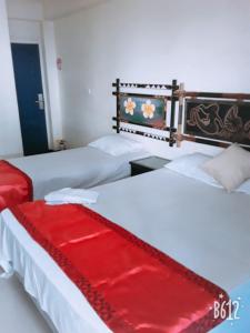 2 camas con una manta roja encima de ellas en Nadi Airport Transit Hotel en Nadi