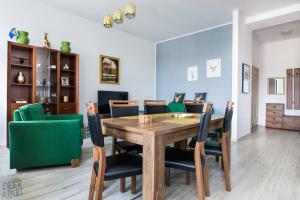 a dining room with a wooden table and green chairs at Deer Apart in Cieszyn