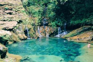 a group of people swimming in a pool in front of a waterfall at Pousada Alvorada in Riachão