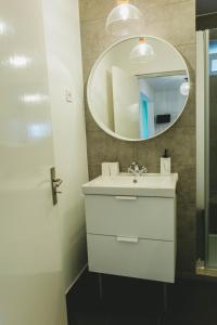 La salle de bains est pourvue d'un lavabo blanc et d'un miroir. dans l'établissement Jasmim, à Setúbal
