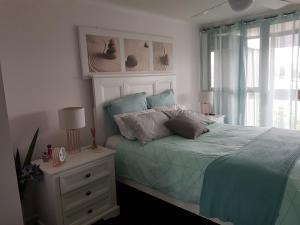 a bedroom with a bed with a blue comforter and a window at Trafalgar Towers in Maroochydore