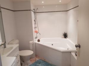 baño blanco con bañera y aseo en Trafalgar Towers en Maroochydore