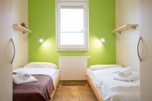 ペルツァーハケンにあるFeriendorf Südstrand Haus 33の緑の壁と窓が特徴の客室で、ベッド2台が備わります。