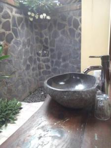 Baño con lavabo de piedra y pared de piedra en Pondok Rahayu Guest House, en Pemuteran