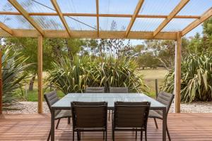 a table and chairs on a deck with a pergola at 170 Hazards View Drive - Unit 2 in Coles Bay