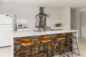a kitchen with a counter with a sink and stools at 170 Hazards View Drive - Unit 2 in Coles Bay
