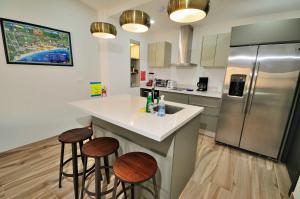 a kitchen with a refrigerator and two bar stools at Jaco Central Condos Villas Paraiso in Jacó