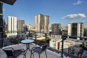 Brisbane One Apartments by CLLIX في بريزبين: بلكونه فيها طاوله وكرسيين ومدينه