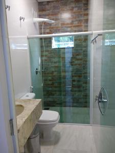 a bathroom with a toilet and a glass shower at Pousada das Cachoeiras in Alto Paraíso de Goiás