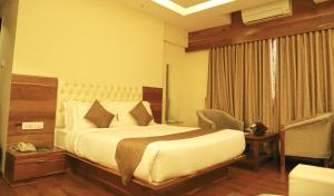 a hotel room with a bed and a chair at Sai Neem Tree Hotel in Shirdi +64 photos