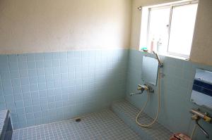 a blue tiled bathroom with a shower and a window at Taikoji Shukubo Hostel in Ise