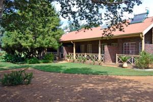a brick house with a red roof and a yard at Magalies Tranquil Haven in Hekpoort