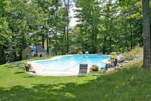 a large swimming pool in a yard with chairs at Okemo Trailside 6A in Ludlow