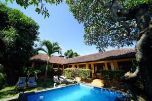 a house with a swimming pool in front of it at Mangga Bungalow in Sanur