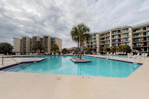 une grande piscine avec un palmier devant les bâtiments dans l'établissement Palmetto Sunrise, à Litchfield Beach