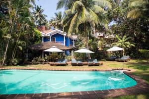 a swimming pool in front of a house with umbrellas at Presa di Goa - Managed by Smith and Appy in Calangute