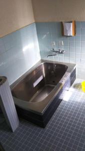 baño con bañera de acero inoxidable y azulejos azules en Taikoji Shukubo Hostel, en Ise