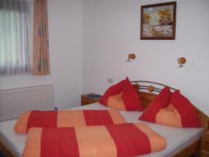 レンゲンフェルトにあるAppartements Romanticaのベッドルーム1室(赤とオレンジの枕が備わるベッド1台付)