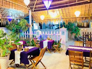 een restaurant met paarse tafels, stoelen en planten bij An Bang Purple Homestay in Hội An
