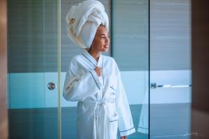 een vrouw in een badjas met een handdoek op haar hoofd bij The Streamliner Hotel Apartment in Toamasina