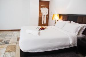 a bedroom with a large white bed with a clock on the wall at The Streamliner Hotel Apartment in Toamasina