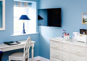 a blue room with a white desk and a tv at Sherbourne House in Attleborough