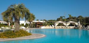 a large swimming pool with a palm tree and tents at Agriturismo La Fattoria in Otranto