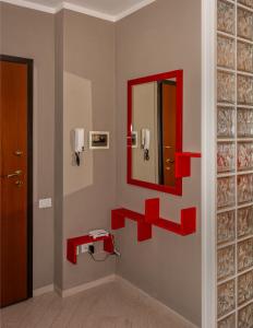 baño con estantes rojos y espejo en la pared en Appartamenti Velez, en Pisa