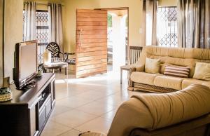 a living room with a couch and a tv at Seokobale Guesthouse in Rustenburg