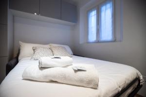 un letto bianco con asciugamani e finestra di Apartment Clusone 1 a Milano