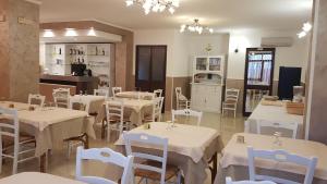 a restaurant with white tables and chairs and a kitchen at Albergo Primavera in Porto Cesareo