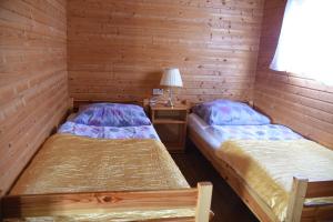two beds in a room with wooden walls at Nestor Domki in Mrzeżyno +7 photos