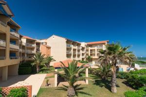 a view of the courtyard of a resort with palm trees at Vacancéole - Résidence Alizéa Beach in Valras-Plage