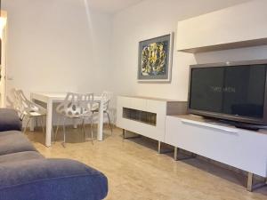 a living room with a tv and a table with chairs at Apartamento en playa Gandia con piscina y parking in Playa de Gandia