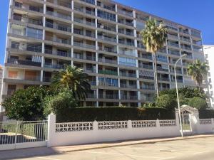 a large building with palm trees in front of it at Apartamento en playa Gandia con piscina y parking in Playa de Gandia